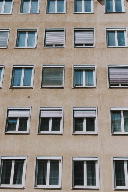 A city building exterior showcasing uniform windows with various window coverings.