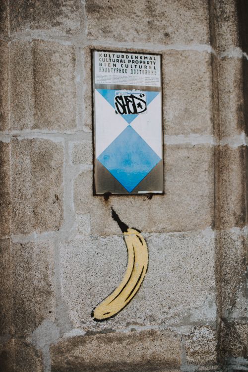 Free Graffiti banana next to cultural property sign on a stone wall, outdoors. Stock Photo