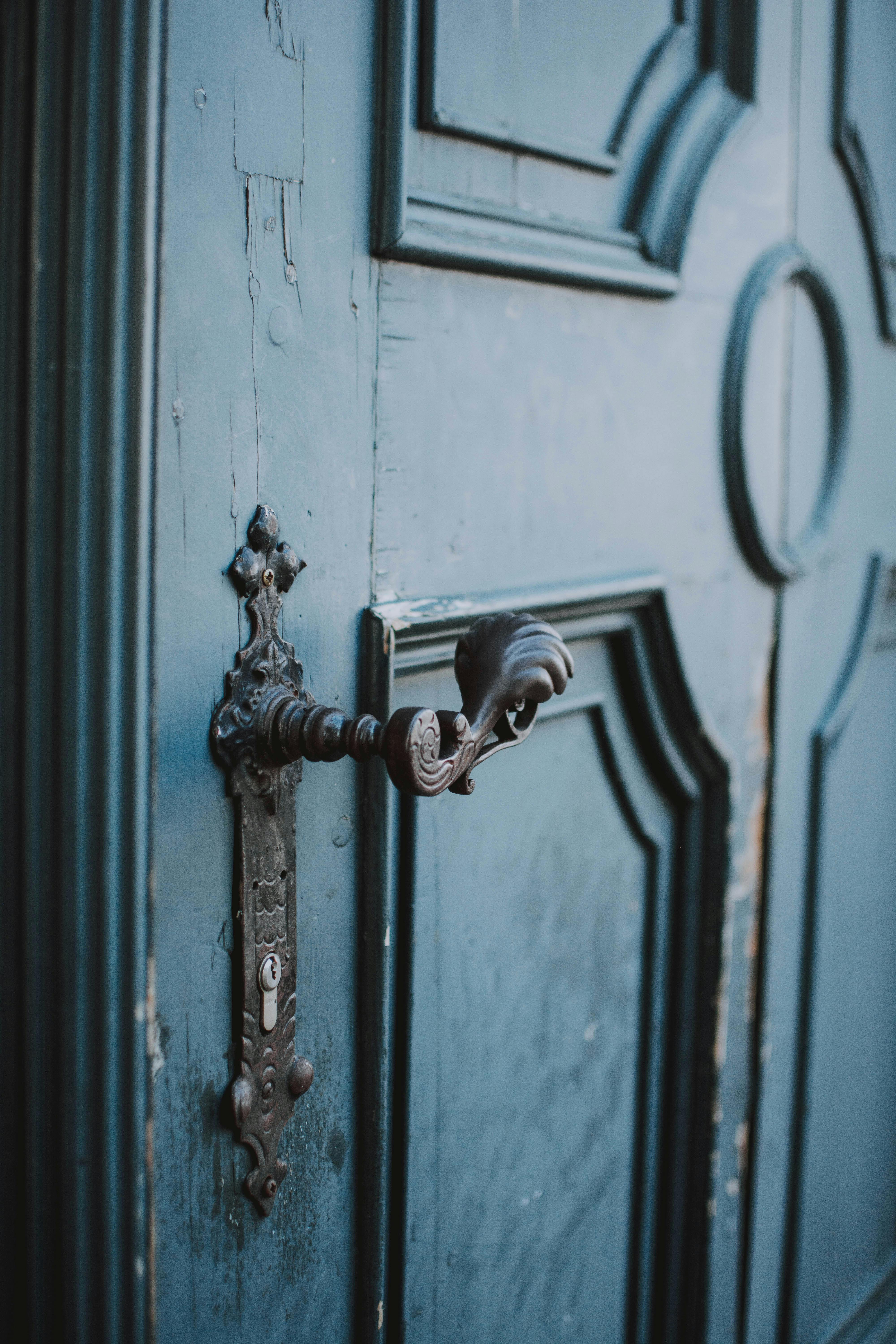 Close-up of an ornate metal handle on a vintage wooden door.