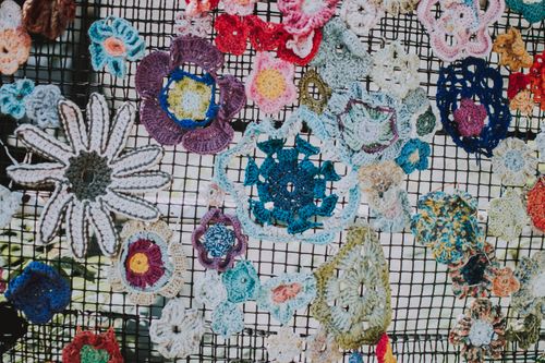 Free Vibrant crocheted flowers arranged on wire mesh, showcasing intricate knitting craftsmanship. Stock Photo