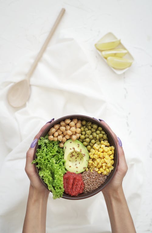 Woman Holding a Bowl with Vegetables and Avocado 