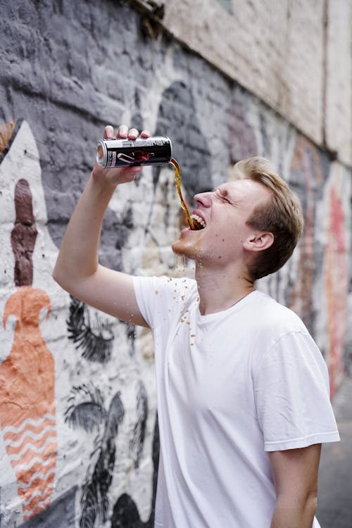 A Man in a White Shirt Pouring a Drink in His Mouth