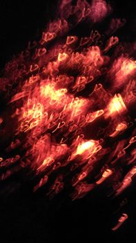 Vibrant abstract image of blurred red lights creating heart shapes on a dark background.