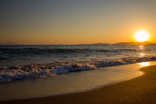 Rough Sea and Wet Sandy Beach with Yellow Sun Reflection