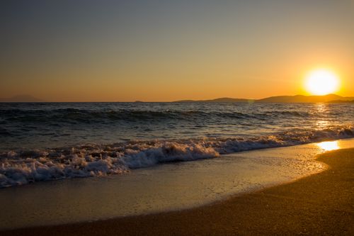 Free A captivating image of a golden sunset over a tranquil beach with gentle waves. Stock Photo