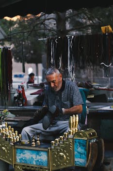 Man shines shoes at an ornate booth in an outdoor urban setting, showcasing traditional craftsmanship.