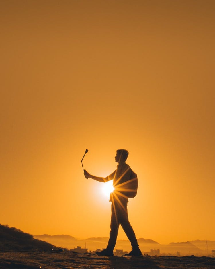 Man Taking Picture At Sunset