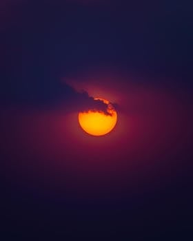 Captivating view of a glowing orange full moon partially covered by clouds against a dark night sky.