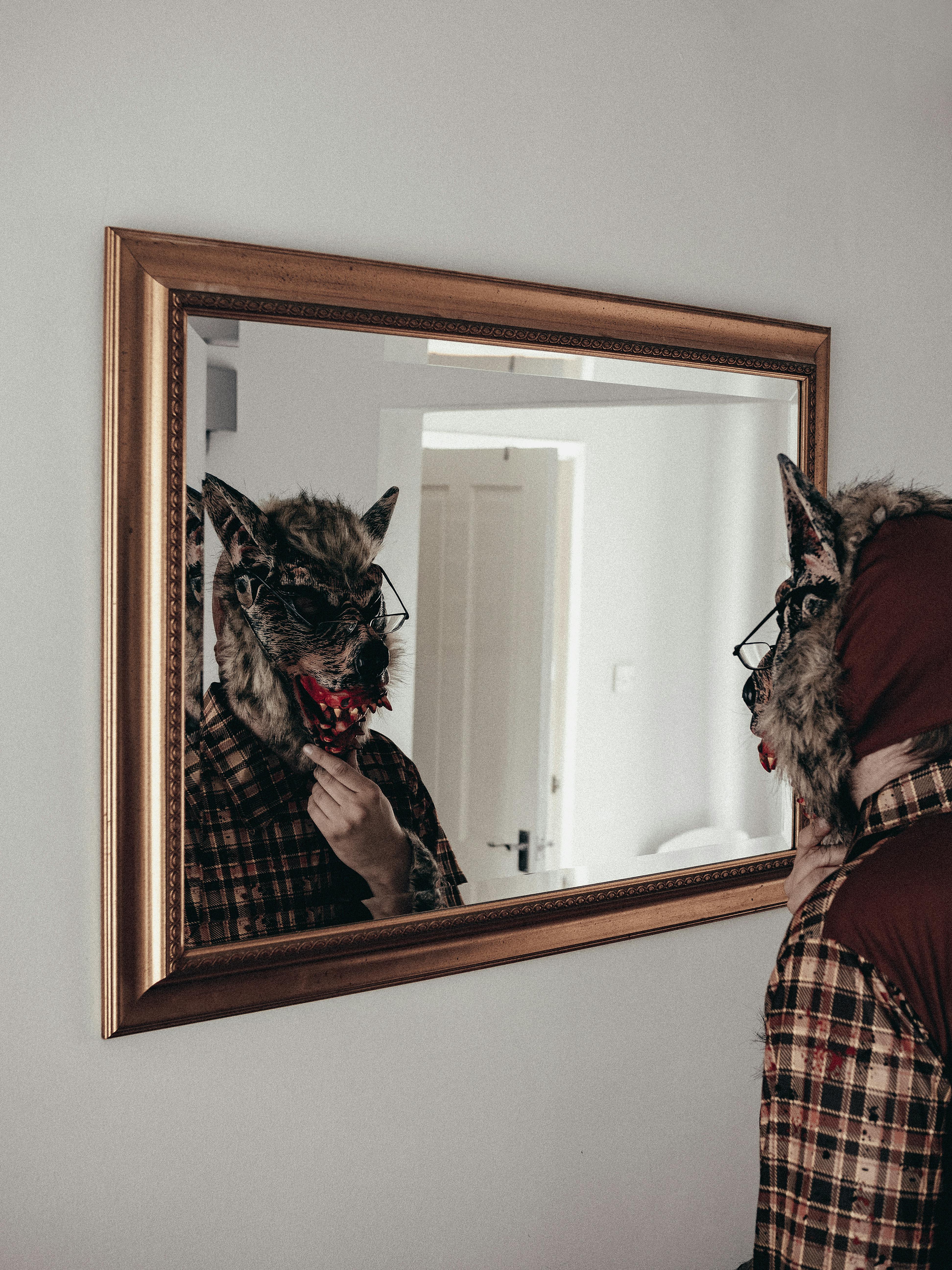 man with a realistic wolf mask looking into the mirror