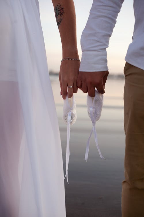 A Couple Holding Pinkies Together Holding Baby Shoes