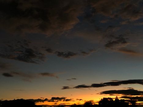 Dark clouds with a scenic sunset silhouette creating a moody skyscape.