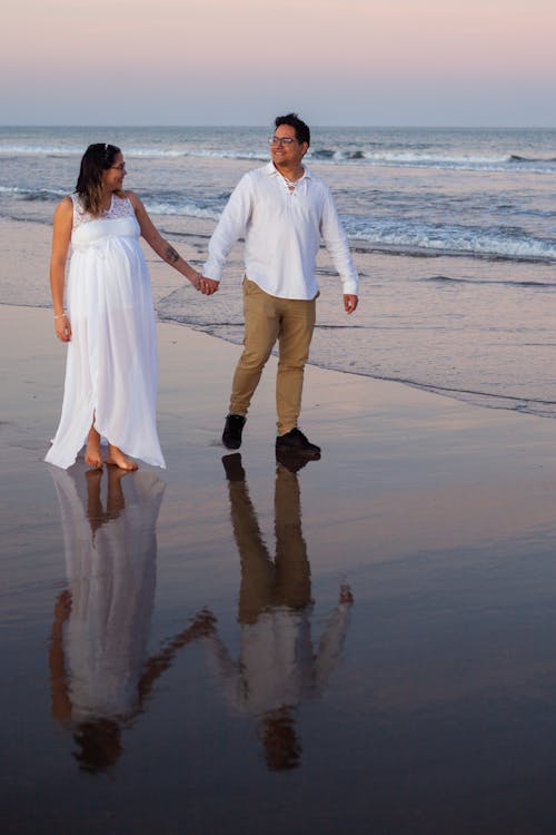 A Couple Standing on the Beach While Holding Hands