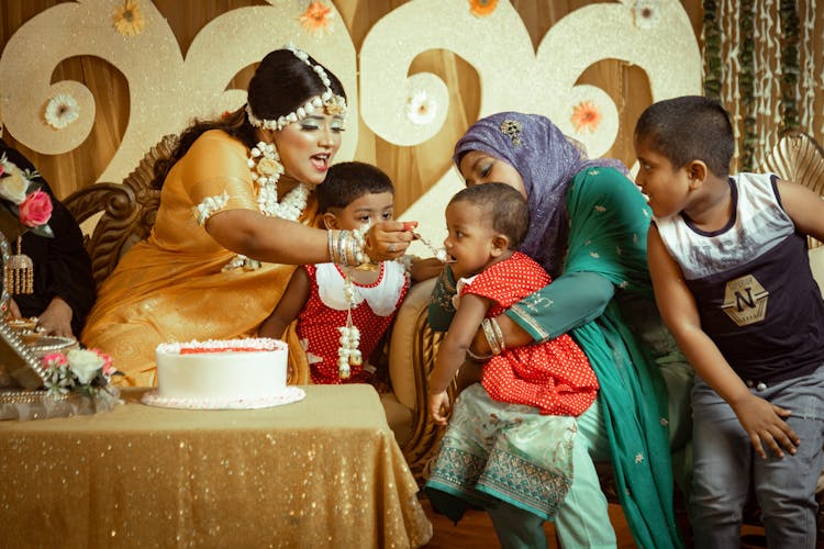 Woman Feeding Kids At Party