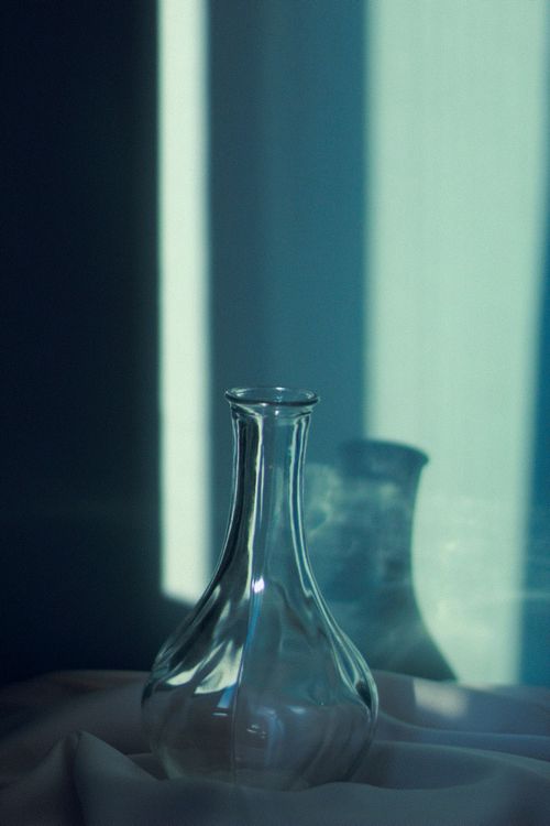 Free A minimalistic glass vase with soft shadows against a serene blue background. Stock Photo