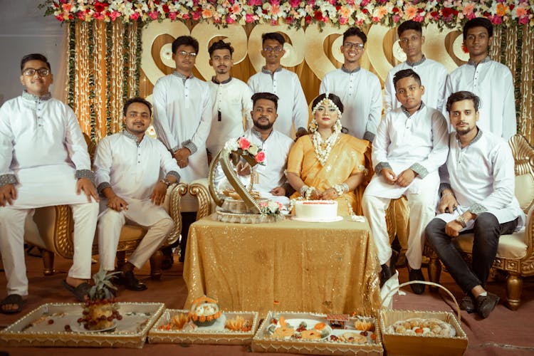 A Woman Sitting Surrounded By A Group Of Men And Boys