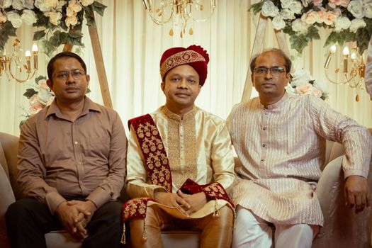 Men Wearing Traditional Clothing Sitting on Sofa, and Garland Decoration in Background