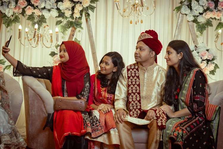 People In Traditional Clothing Sitting On A Couch While Having A Groufie