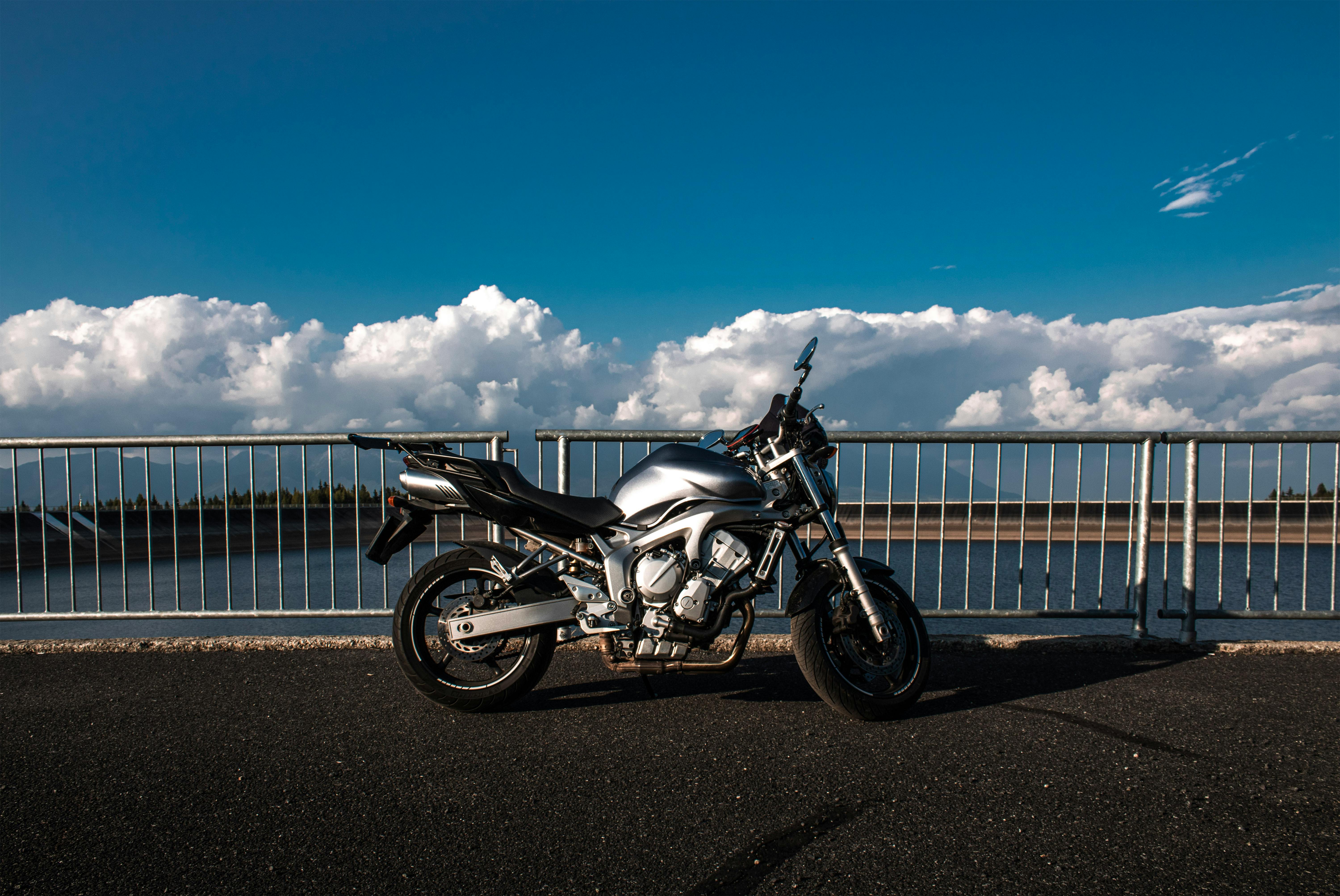 motorbike from side on road in nature by lake and fence in background