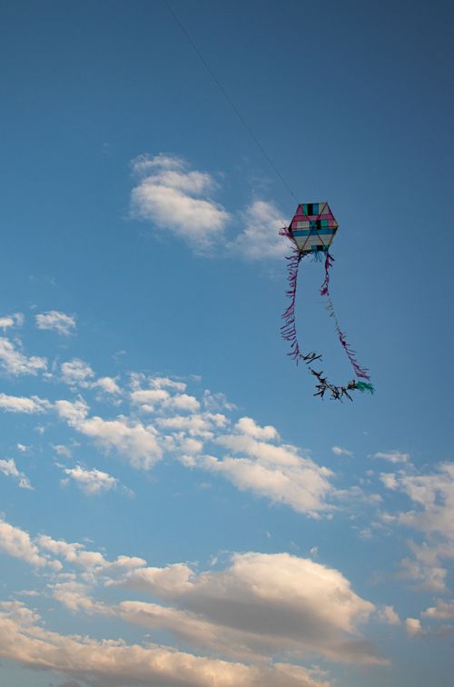 Free A vibrant kite soaring against a blue sky with scattered clouds, symbolizing freedom and leisure. Stock Photo
