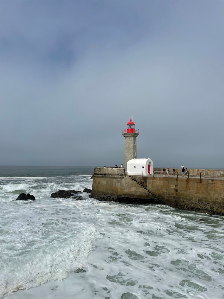 Lighthouse At End Of Pier Extending Into Sea