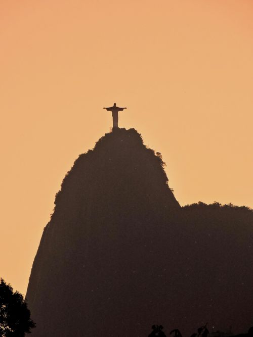 Free Silhouette of Christ the Redeemer statue against a warm sunset in Rio de Janeiro, Brazil. Stock Photo