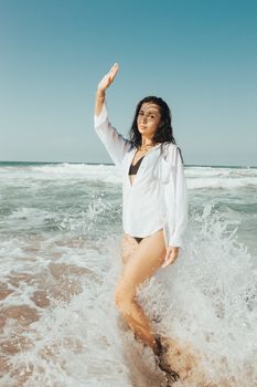 A woman in a bikini enjoys splashing waves at a beach in İstanbul, Turkey.