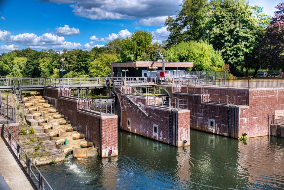 A brick water lock system under a blue sky, surrounded by trees and water.