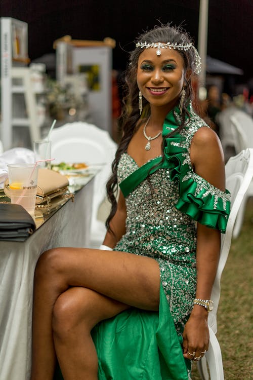 A Woman in Silver and Green Evening Dress Sitting at a Table