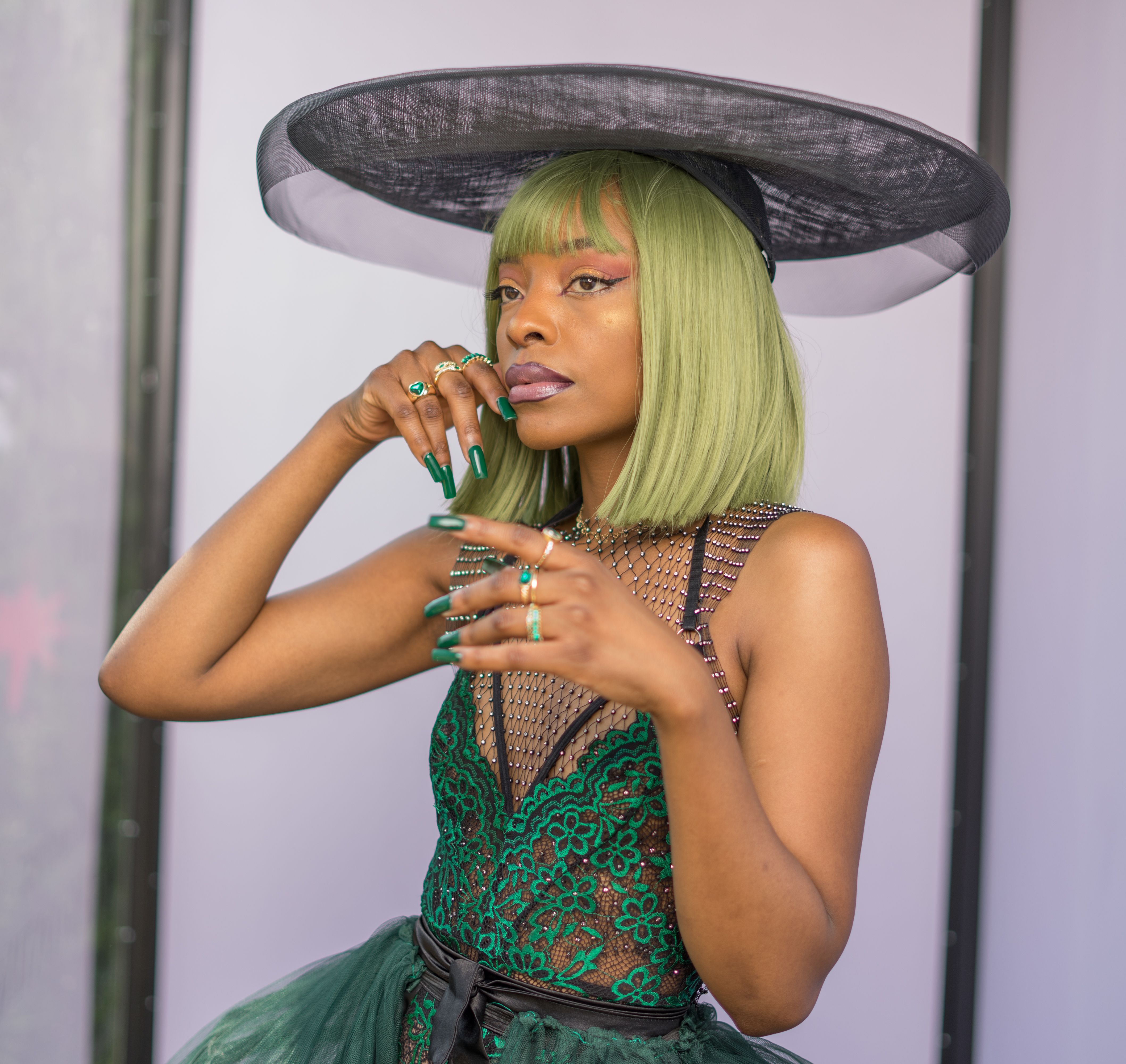 Stylish portrait of a fashionable woman in a green dress with a chic hat, showcasing elegance and style.
