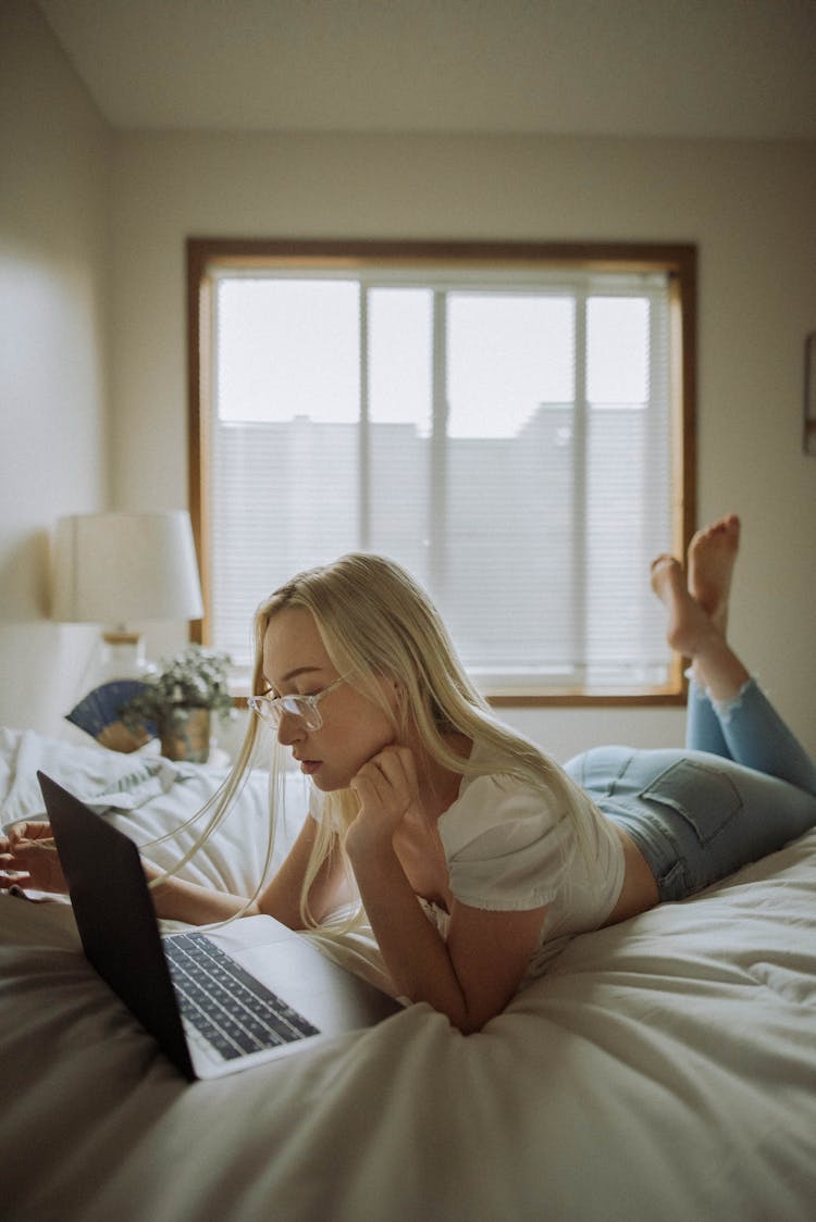 Woman Lying On The Bed And Using Laptop 