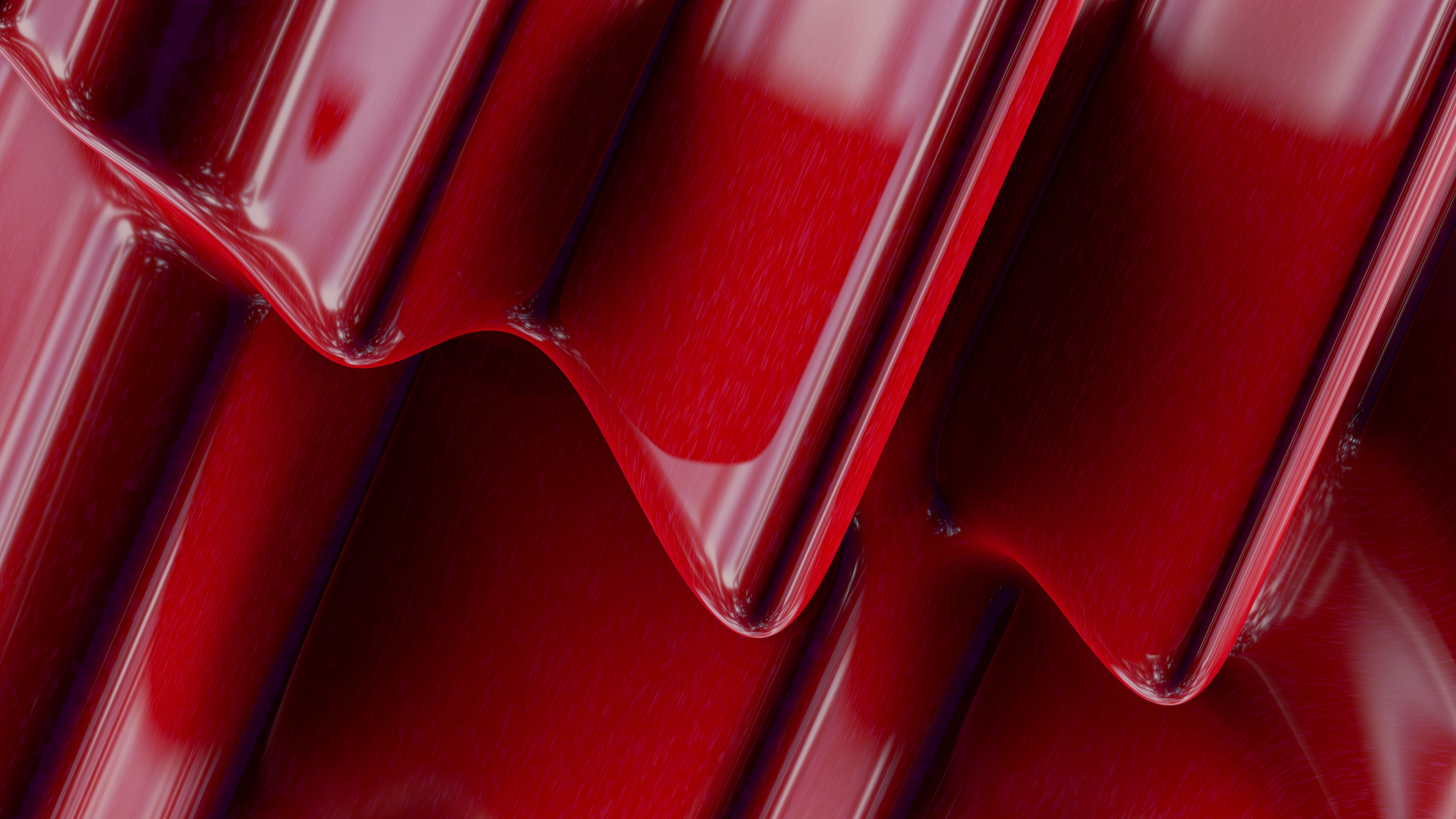 Close-up of an abstract red metallic surface with glossy reflections.