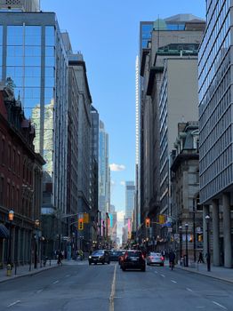 Downtown Toronto street scene featuring high-rise buildings and urban traffic under a clear blue sky.