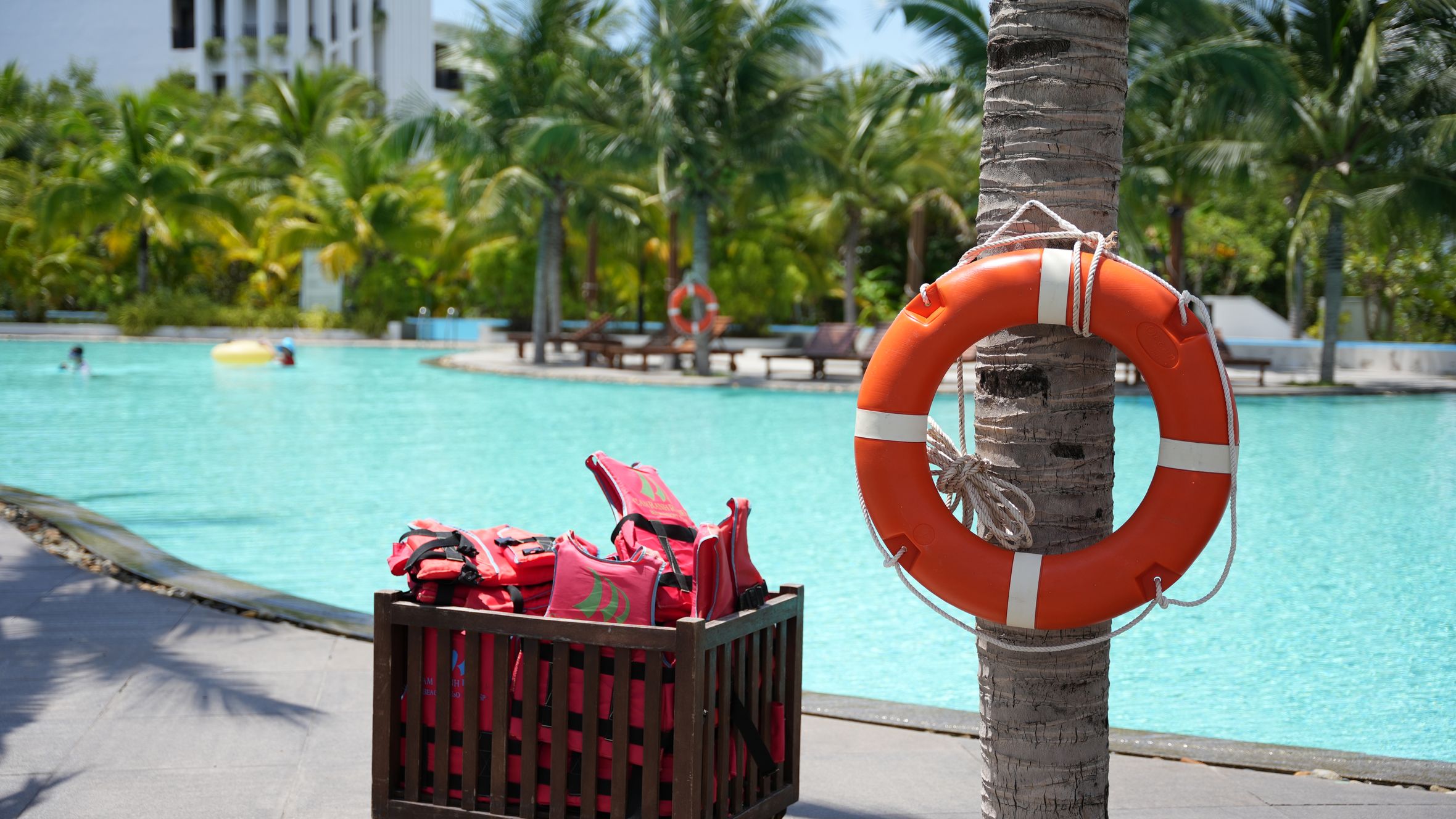 A serene resort pool scene in Vietnam featuring life vests and a lifebuoy for safety.