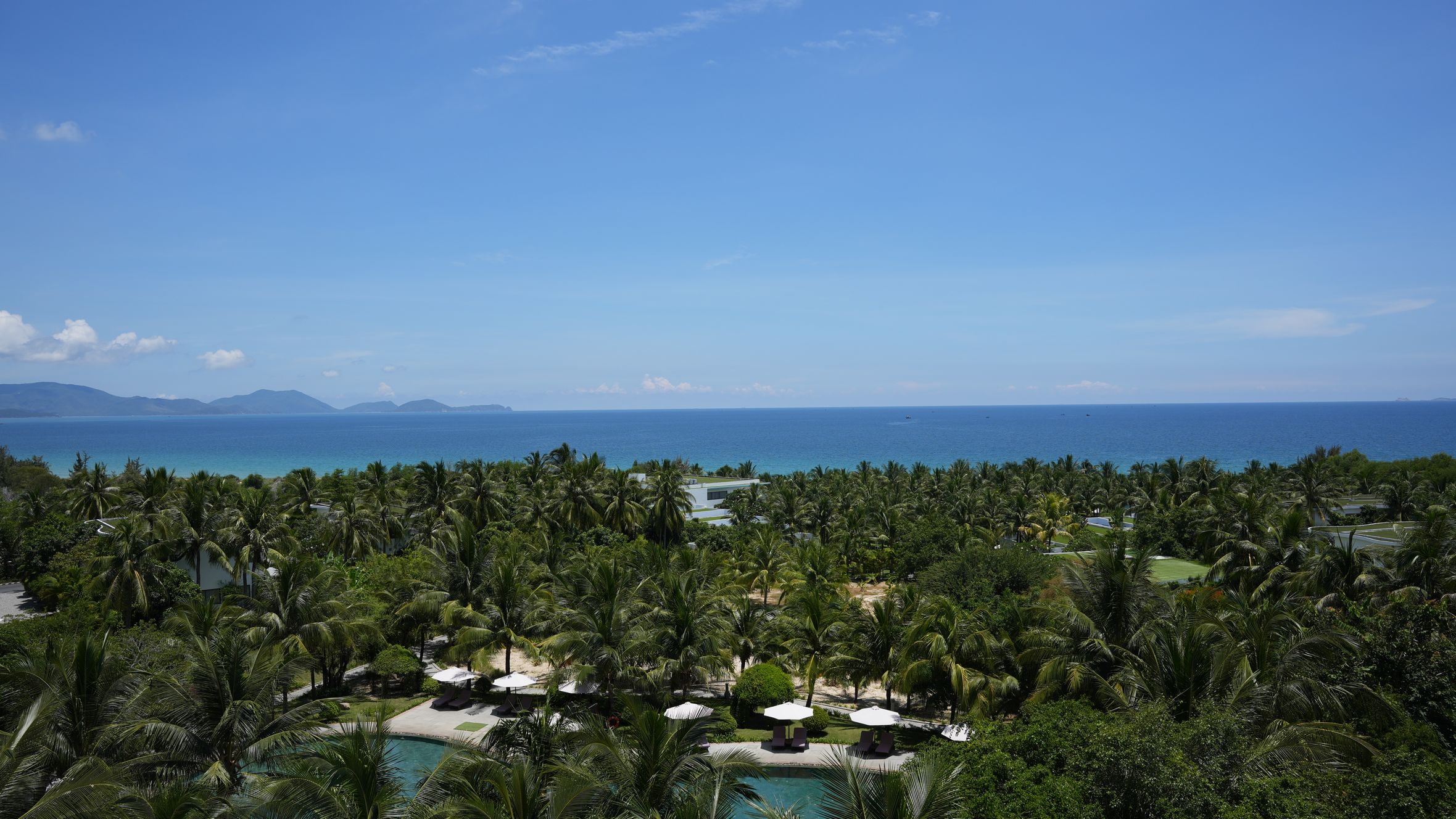 A stunning beachfront panorama in Cam Ranh, Vietnam, featuring palm trees and azure waters.