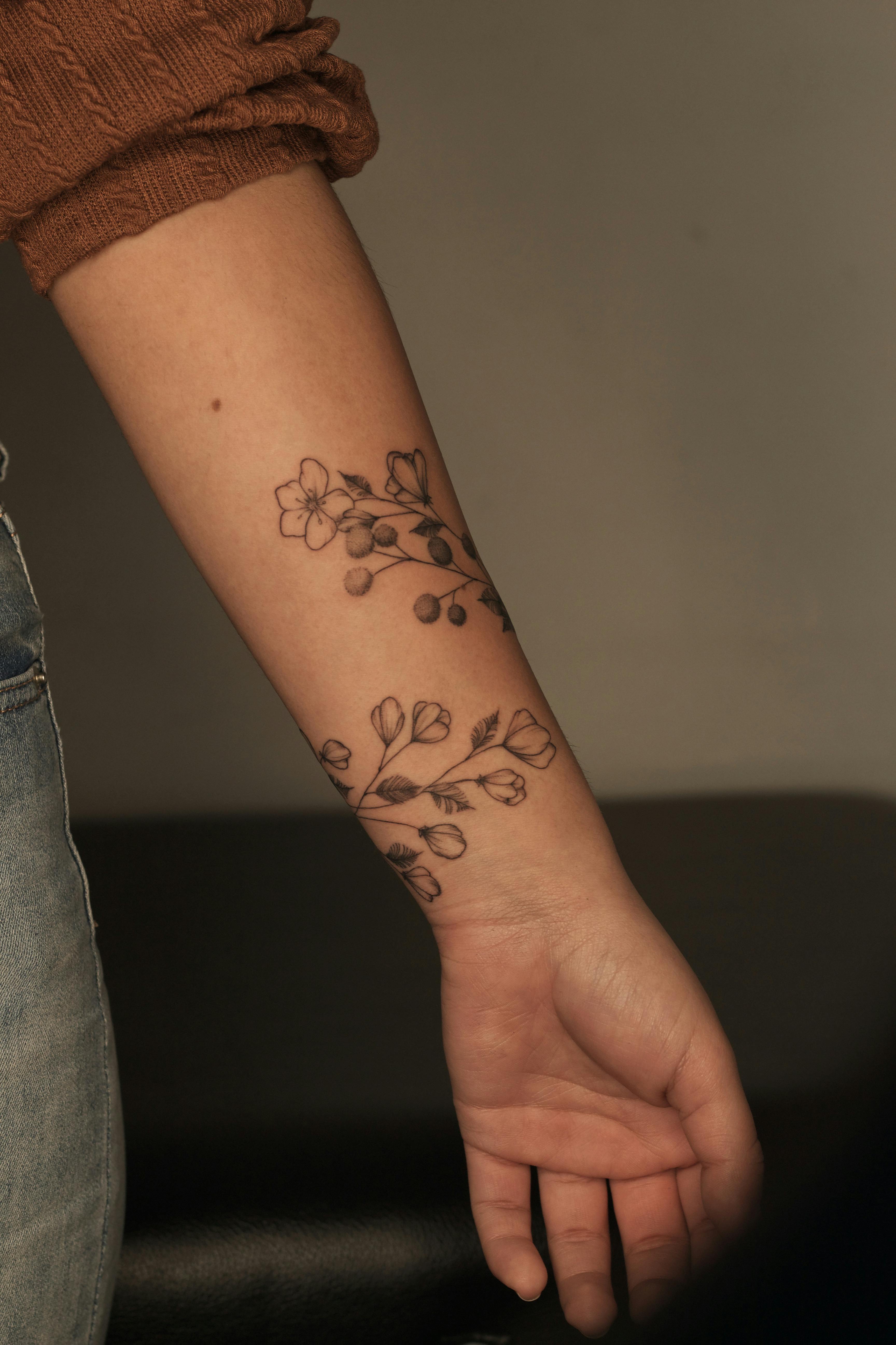 Close-up view of a floral tattoo on a person's forearm, showcasing intricate details.