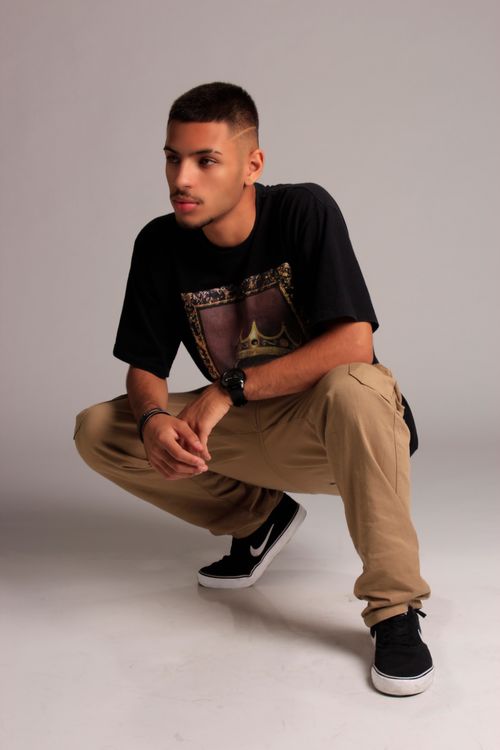 Free Young man in stylish black shirt and brown pants posing in a studio setting. Stock Photo
