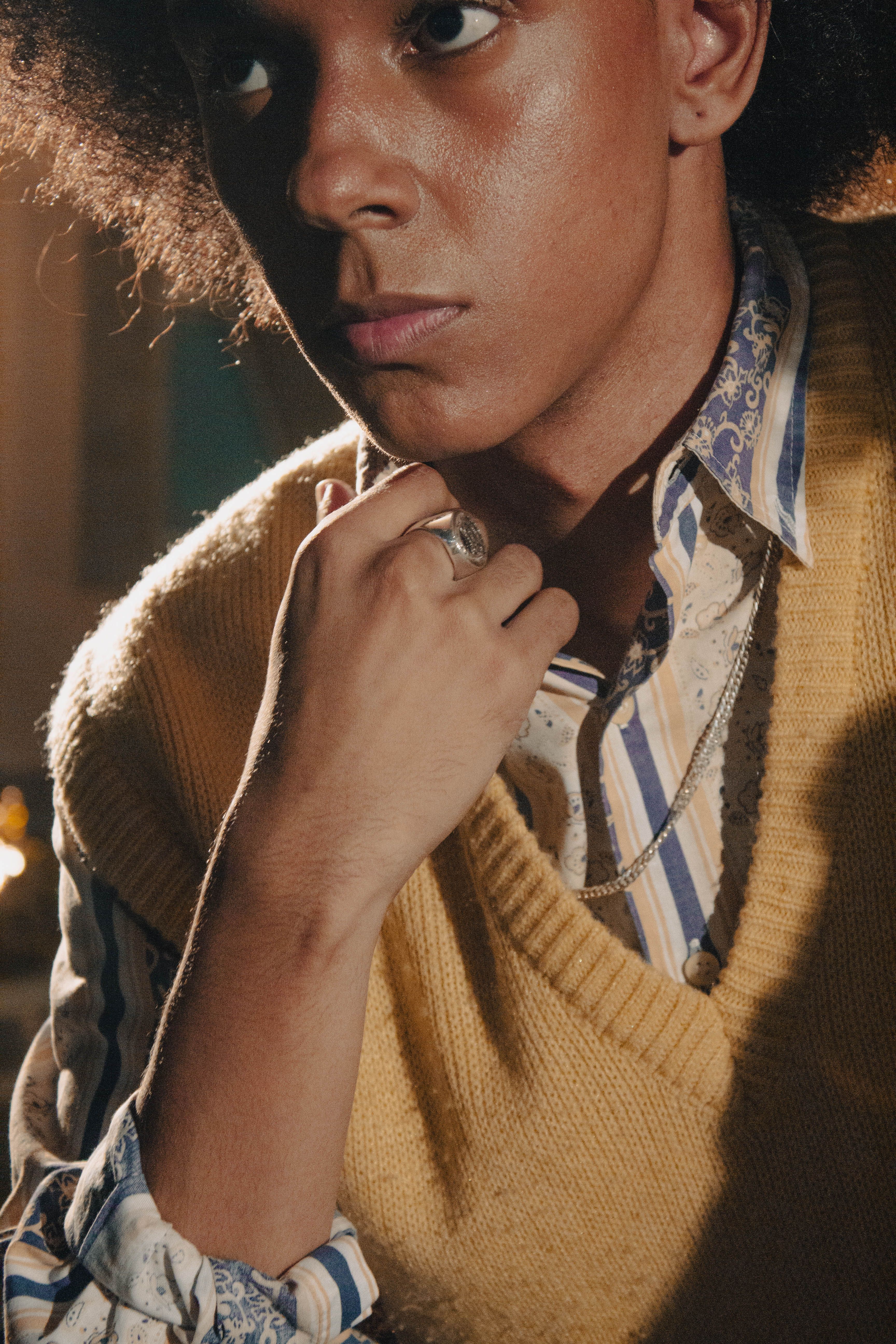 A fashionable young man indoors, showcasing a vintage look with retro patterns and elegant accessories.