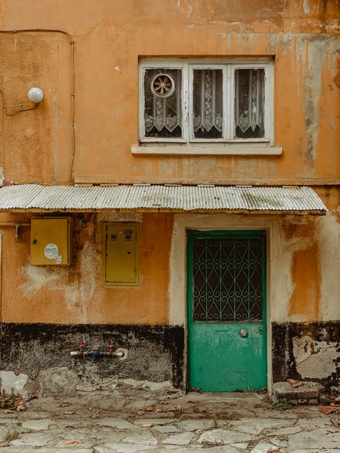 Vintage exterior showcasing a green door and window in a weathered building facade.