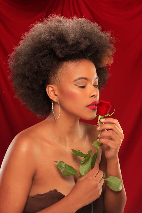 Woman Wearing Hoop Earrings Holding a Red Rose