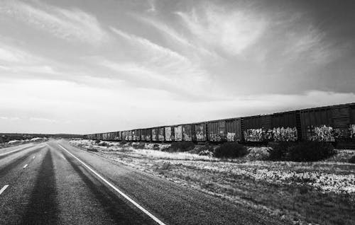 Grayscale Photo of a Road Near Train