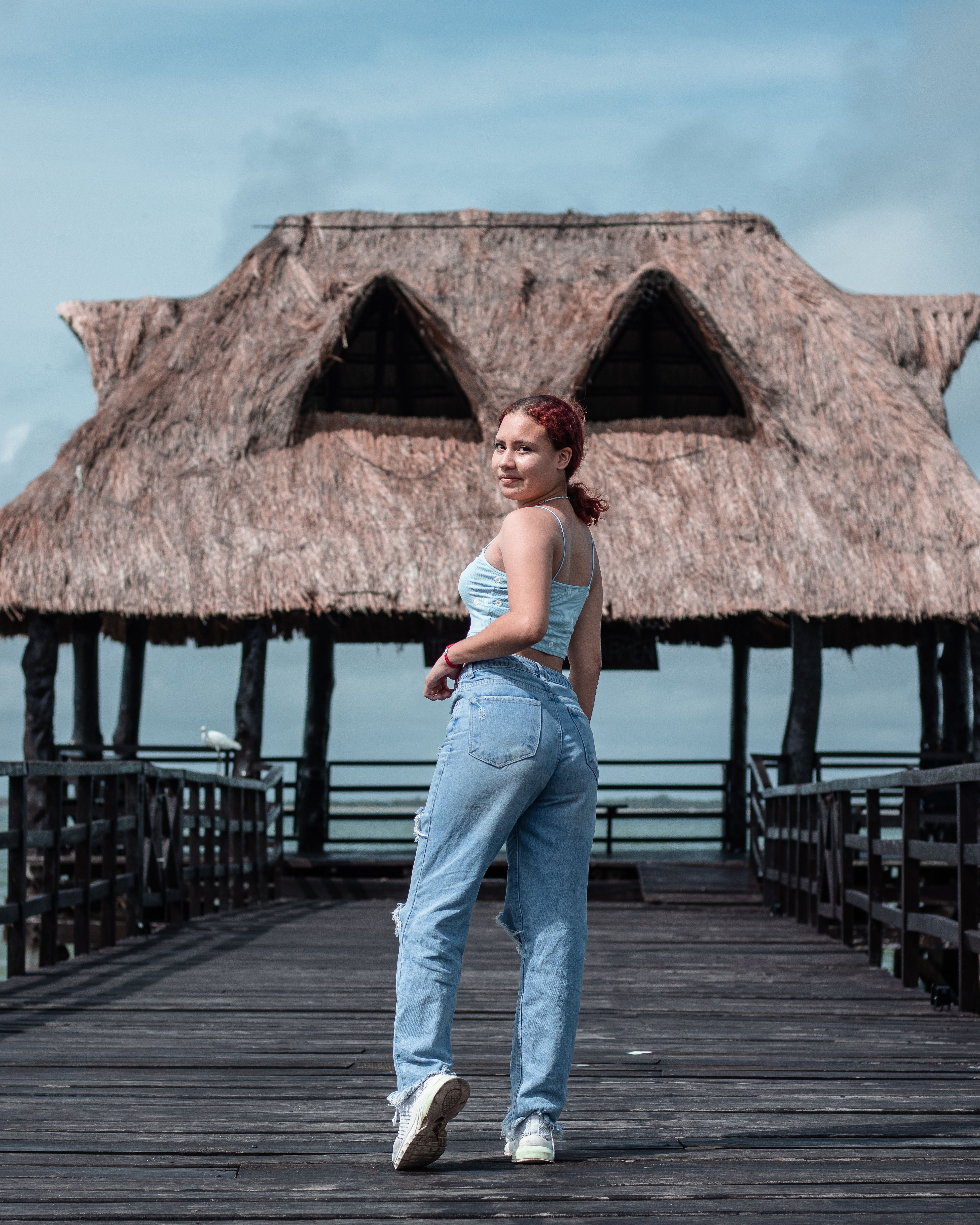 Woman in Blue Tank Top and Denim Jeans Standing on Wooden Deck · Free ...