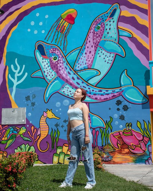 A Woman in Blue Crop Top and Blue Denim Jeans Standing Beside Wallwith Graffiti