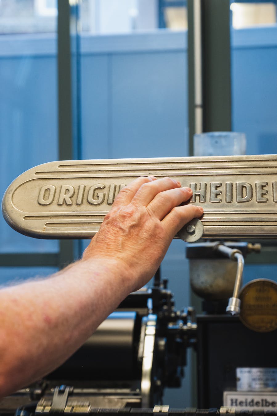Detailed view of a hand operating a vintage Heidelberg printing press in Spira museum.