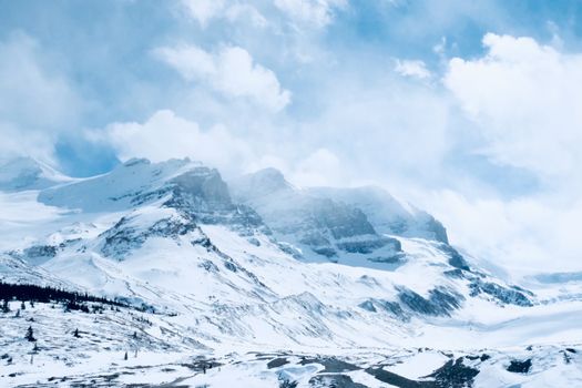 Stunning view of snow-covered mountains under a cloudy sky in Banff National Park, Alberta.