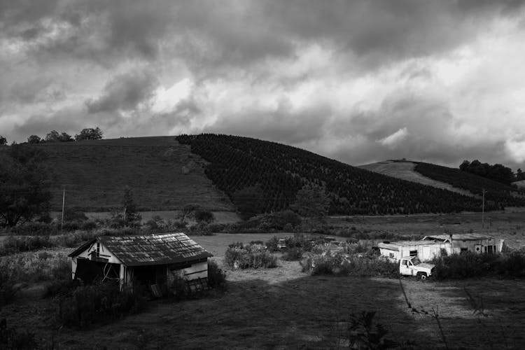 Grayscale Photo Of A Barn Near The Hill