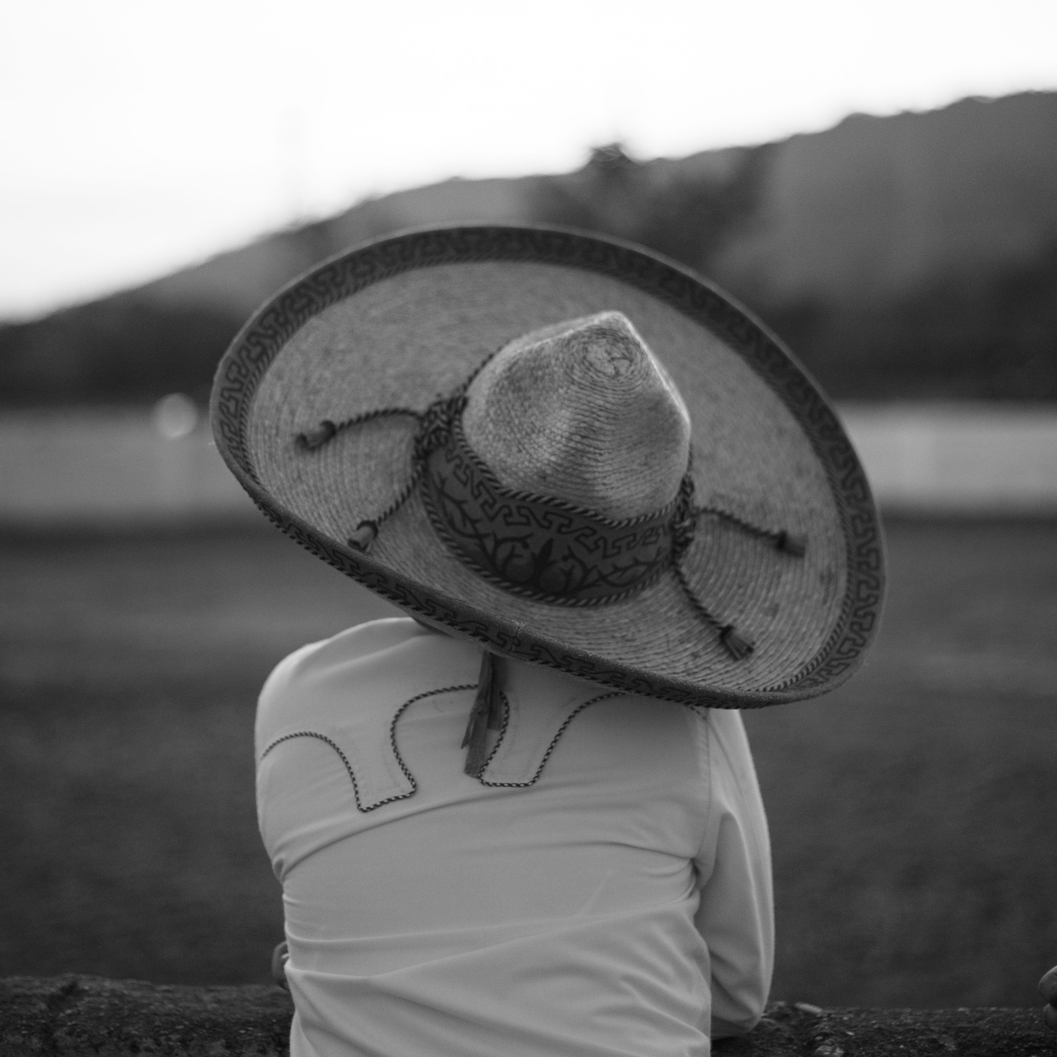Black-and-white image of a person in Poza Rica, Mexico, wearing a large sombrero, captured from behind.