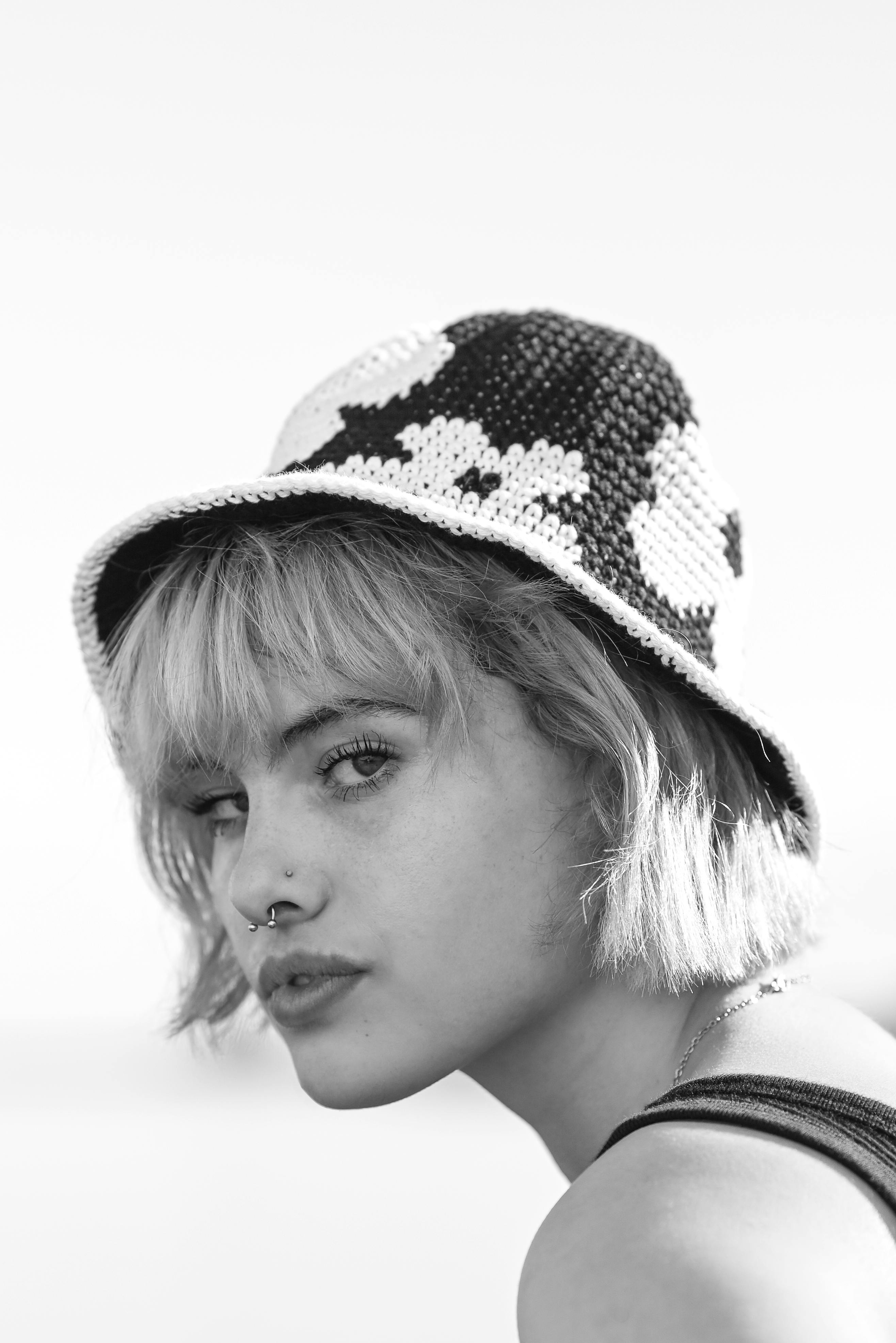 Black and white portrait of woman wearing a knitted hat and nose piercing, in a vertical shot.