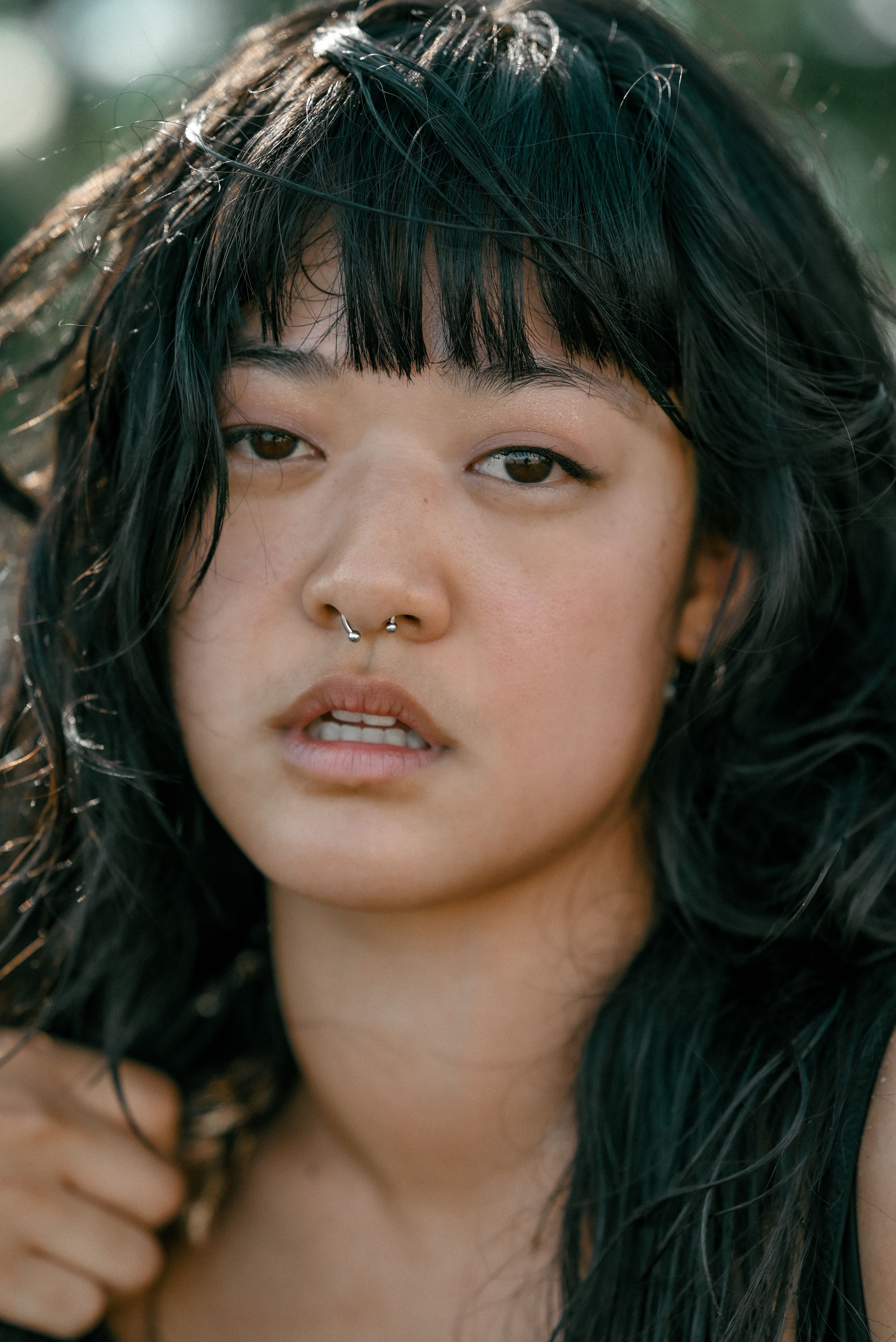 Intimate close-up portrait of a woman with distinctive nose piercing and expressive eyes.