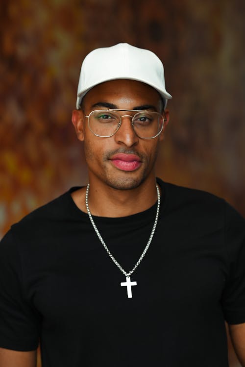 Close-Up Shot of a Man in Black Shirt Wearing White Cap and Eyeglasses