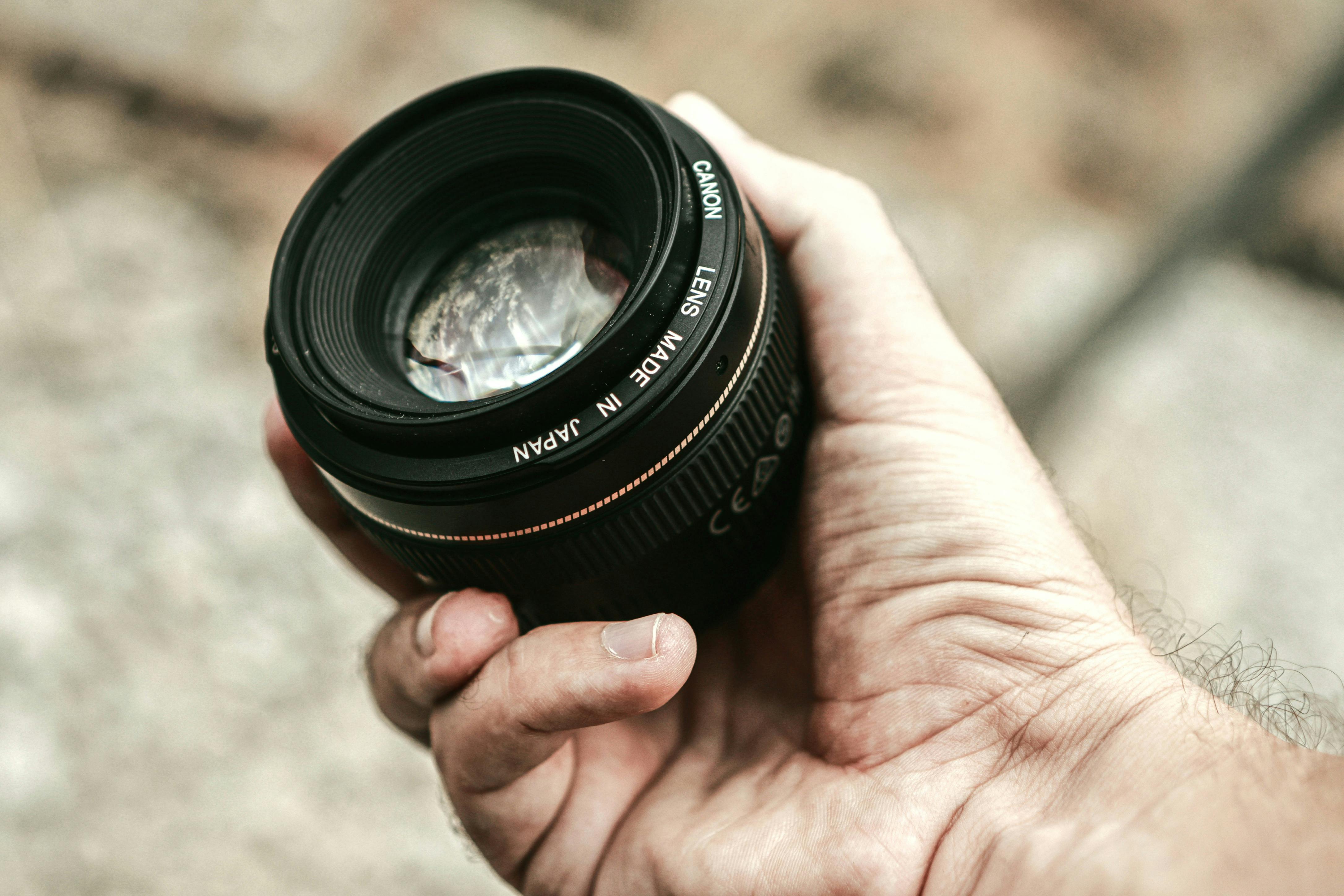 a person holding black camera lens